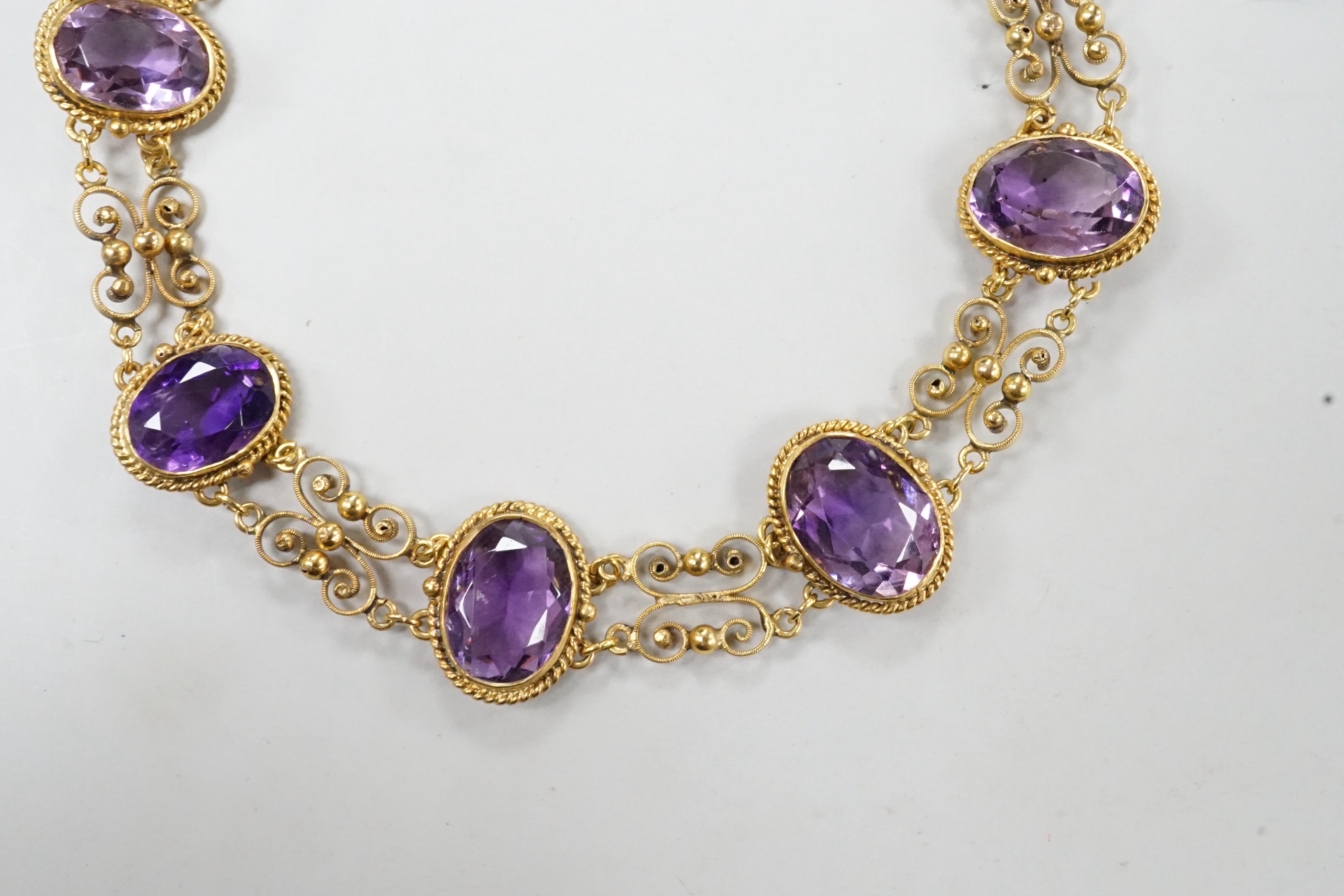 A late Victorian yellow metal and eight stone oval cut amethyst set fancy link bracelet, 18cm, gross weight 9.6 grams.